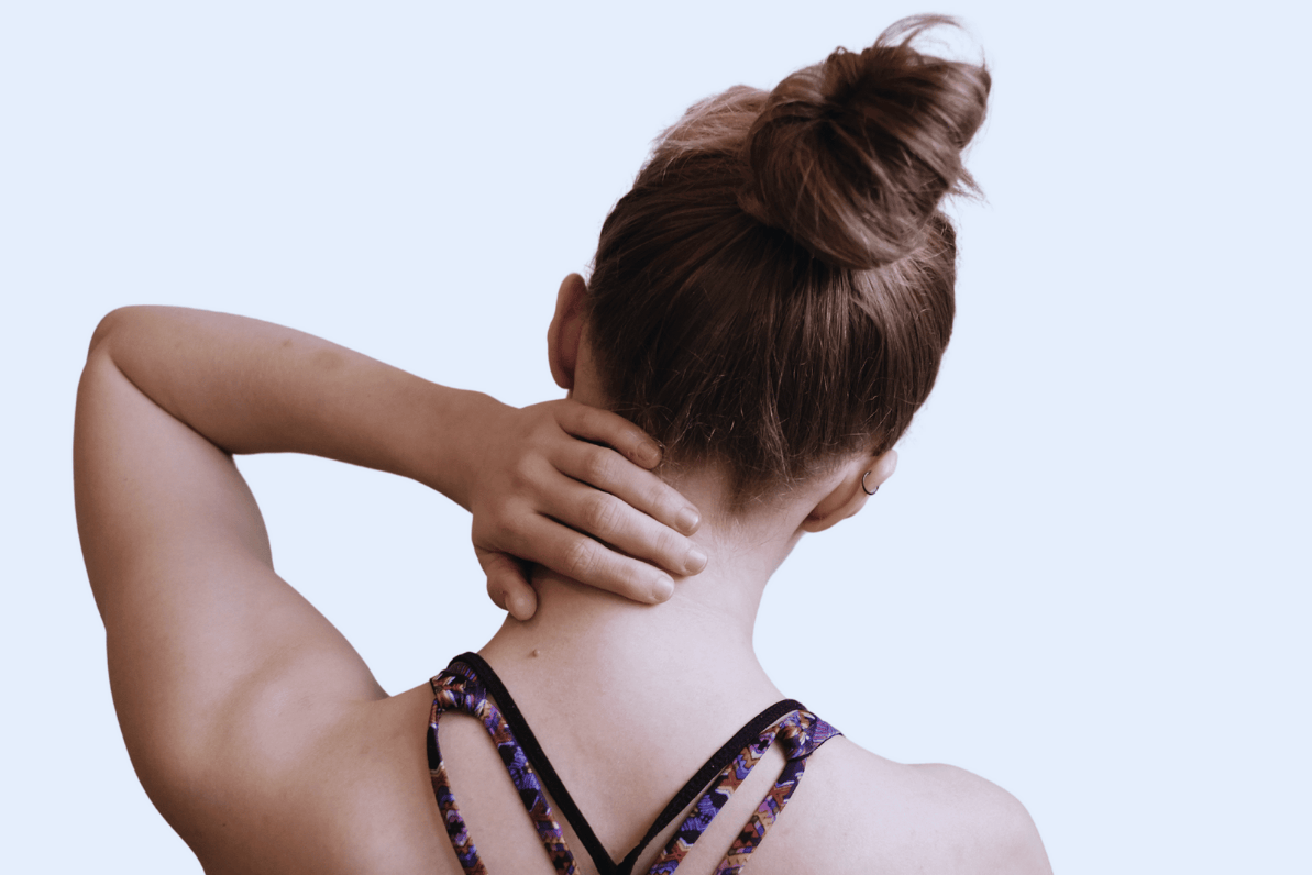 Woman with a bun in her hair touching her neck against a light purple background